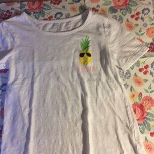 White shirt with pineapple  on and say aloha